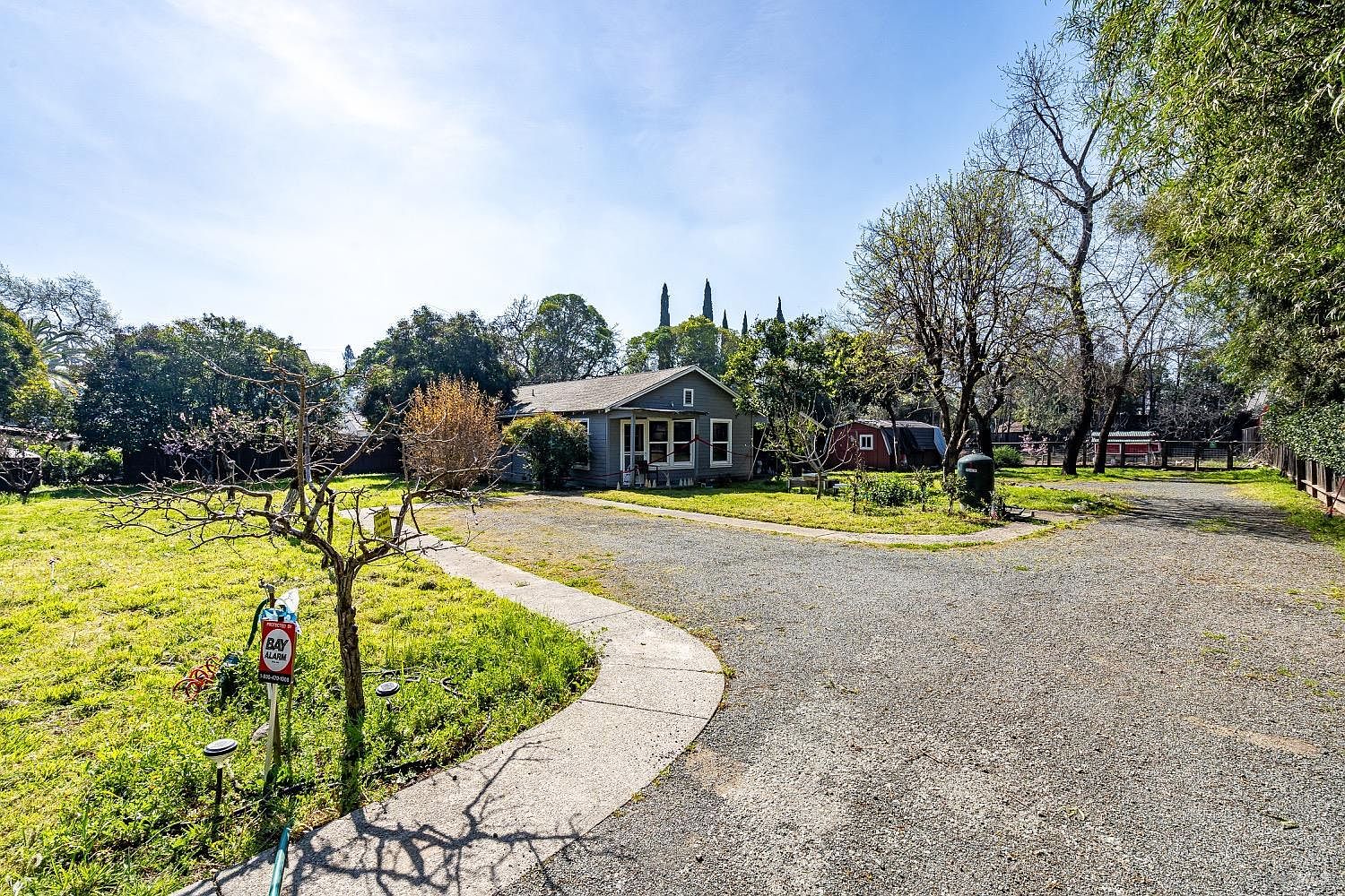 The 1946 cottage with circular driveway, sun on the front facade, framed by trees.