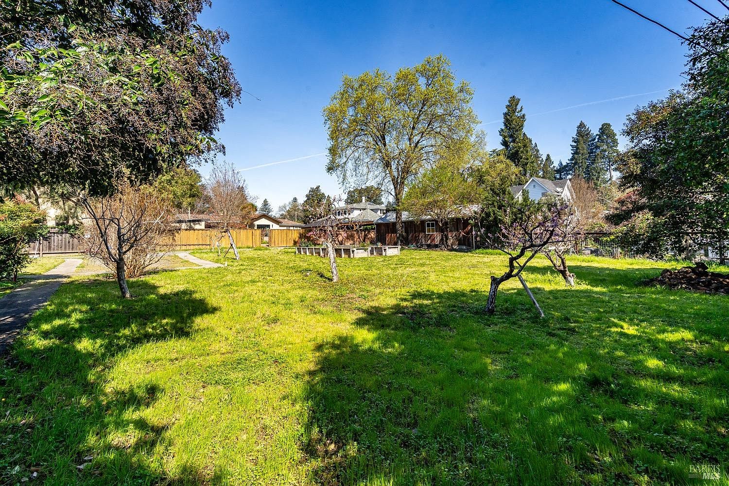 Rear of the lot showing the depth of the parcel and a ranch-style structure beyond.